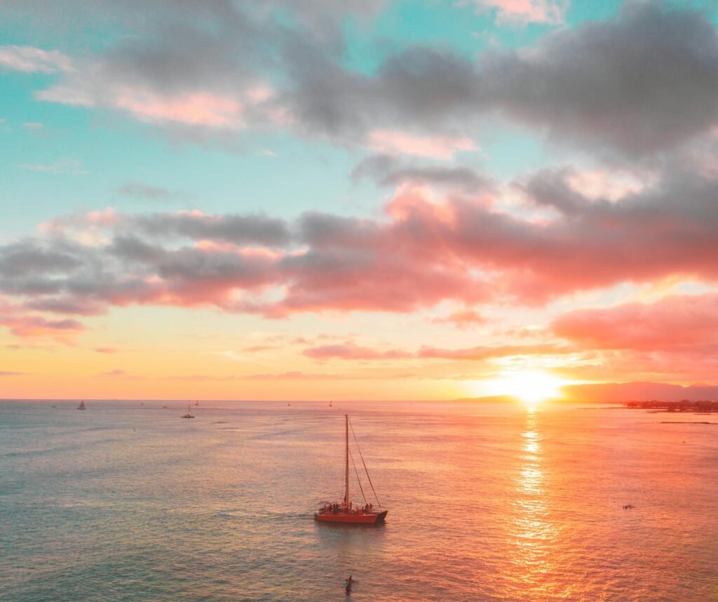 Stunning sunset over the ocean with sailboats and city skyline, capturing vibrant colors and tranquility.